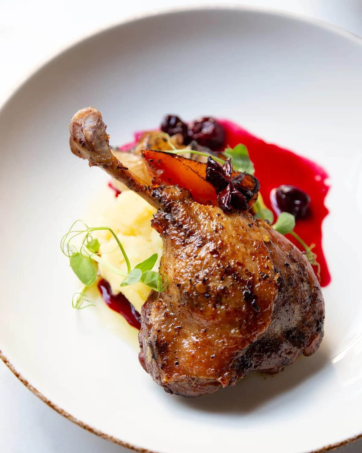 Roast duck leg with cherry sauce on a white plate
